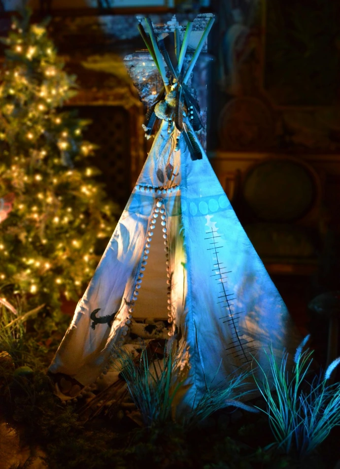 A teepee sitting next to a christmas tree